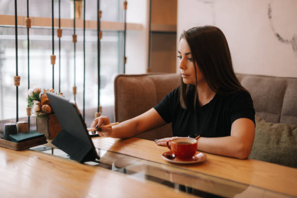 istock Beautiful caucasian woman using a digital tablet while sitting at cafe. 1209276814