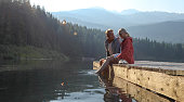 Mature couple relax on wooden pier, looks out across lake