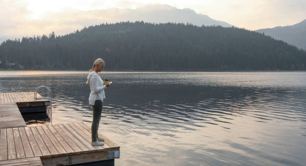成熟した女性は木製の桟橋で一時停止し、湖を見渡す - 11316 ストックフォトと画像
