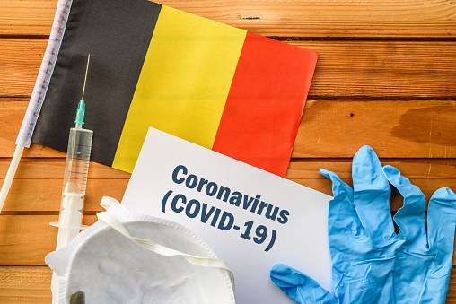 Flag of Belgium, vaccine, face mask for virus, glove and paper sheet with words Coronavirus COVID-19