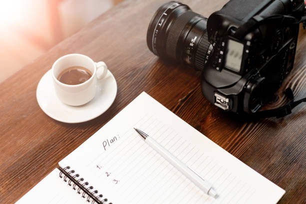 Professional digital camera with notebook and coffee on wooden table