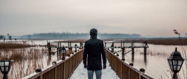 istock Single man wearing coat standing on jetty 1209283518