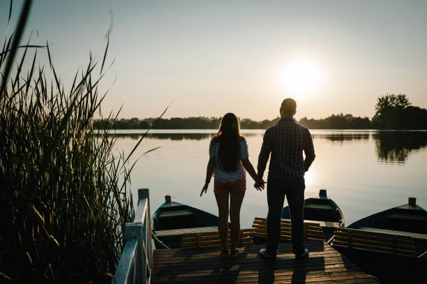 istock Couple holding hands looking in the sunset on pier. Back view. 1209287583