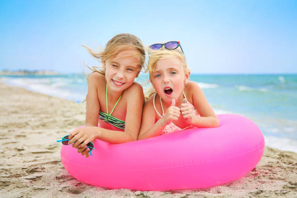 istock Happy girls lying on pink inflatable circle. 1209287810
