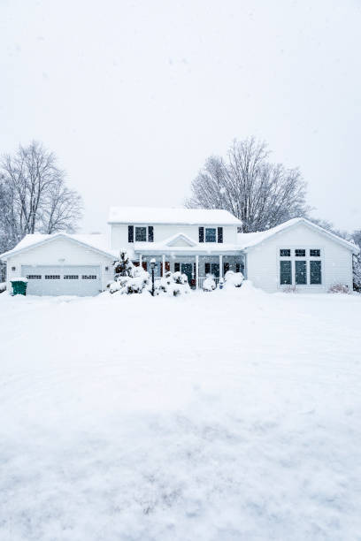 Extreme Blizzard Snow Storm Suburban Colonial Home Front elevation vertical view from the street in front of a colonial style home built in the 1970's. Photo taken during an extreme February winter blizzard snow storm in a suburban residential district neighborhood near the city of Rochester, in western New York State. driveway colonial style house residential structure stock pictures, royalty-free photos & images