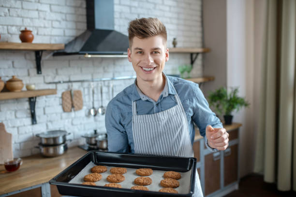 istock Young man with baking sheet of home baking in hands. 1209290375