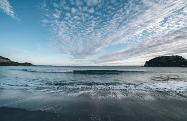 Opposing patterns of clouds in sky and backwash of waves on sand. Opposing patterns of clouds in sky and backwash of waves on sand at Mount Maunganui Main Beach, Tauranga New Zealand. mount maunganui stock pictures, royalty-free photos & images
