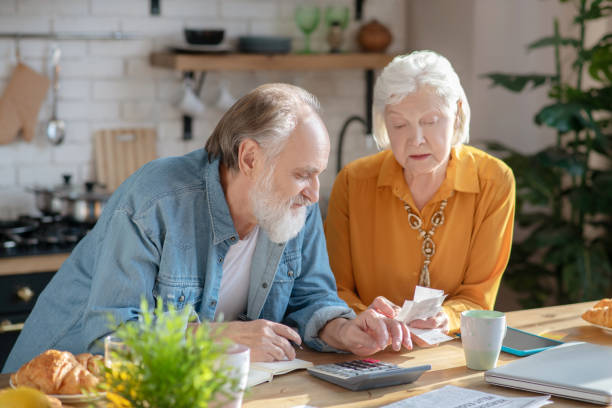 istock Elderly married couple making calculations together and looking involved 1209299534