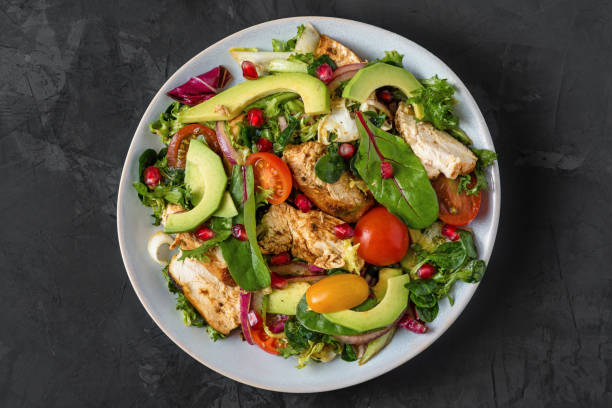 fresh salad with chicken breast, avocado, pomegranate seeds and tomato on black background. healthy diet food - chicken salad grilled chicken grilled imagens e fotografias de stock