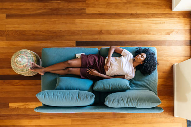 молодая черная леди спит на диване дома - furniture high angle view armchair above стоковые фото и изображения