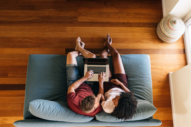 istock Multiethnic lovers sitting on couch with laptop together 1209300105