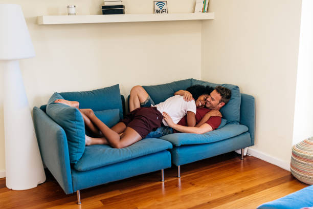istock Idyllic multiethnic couple enjoying each other on sofa at home 1209300143