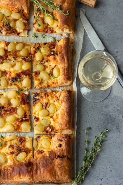 istock Deliciously tart made with puff pastry, caramelized onion, cheese, thyme and green grape. Flatbread with grapes. 1209308320