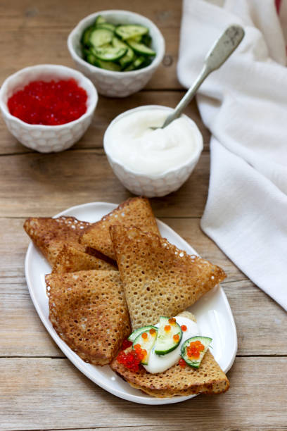 istock Rye and whole grain pancakes served with sour cream, caviar and cucumbers. Rustic style. 1209310810