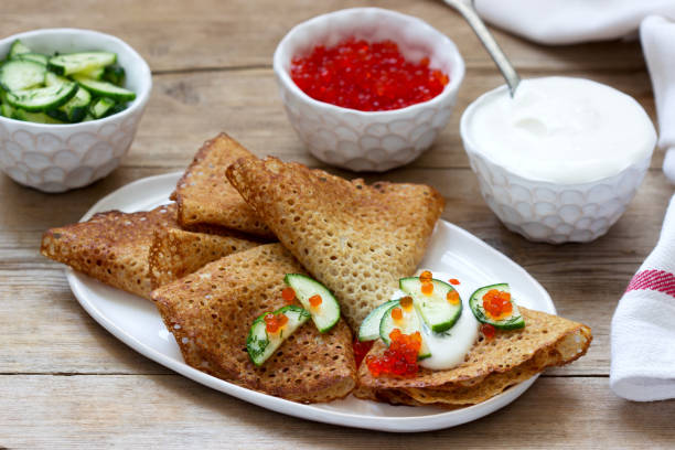istock Rye and whole grain pancakes served with sour cream, caviar and cucumbers. Rustic style. 1209310812
