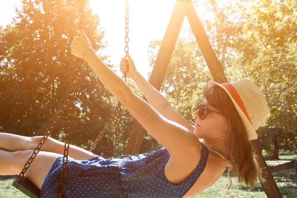 istock Cute young woman enjoying on a swing outdoors in summertime sunlight. 1209311027