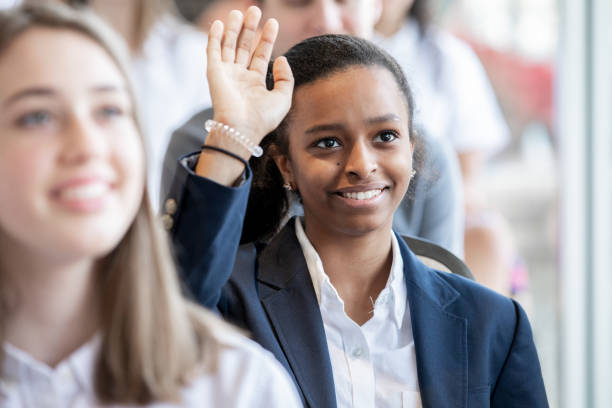 female teenage student raises hand during lecture - adult student college student school uniform student imagens e fotografias de stock