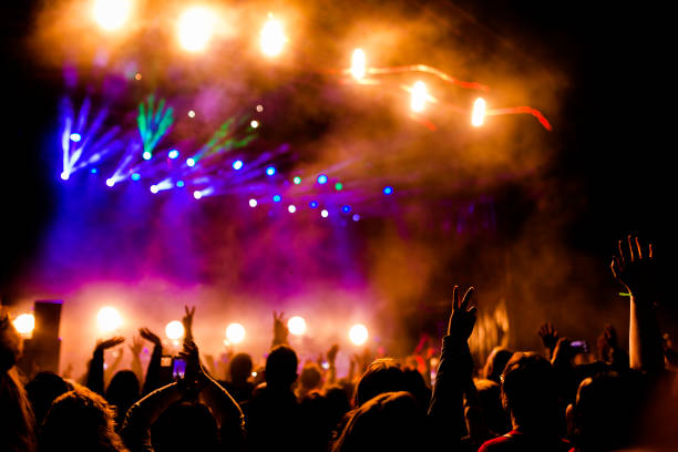 imagen de mucha gente disfrutando de la perfomance nocturna, gran público irreconocible bailando con manos levantadas y teléfonos móviles en concierto. vida nocturna - músico de rock fotografías e imágenes de stock