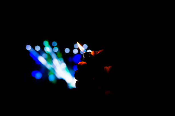 man hand holding a lighter in a night concert performance. fun and lifestyle outdoors - popular music concert performance outdoors crowd imagens e fotografias de stock