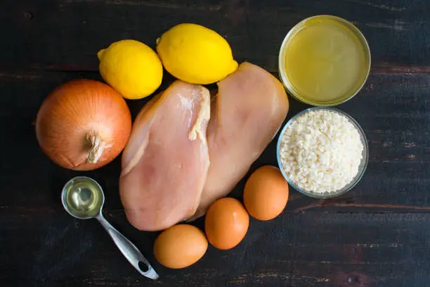 Chicken breasts, arborio rice, lemons, and other raw ingredients for a traditional Greek soup