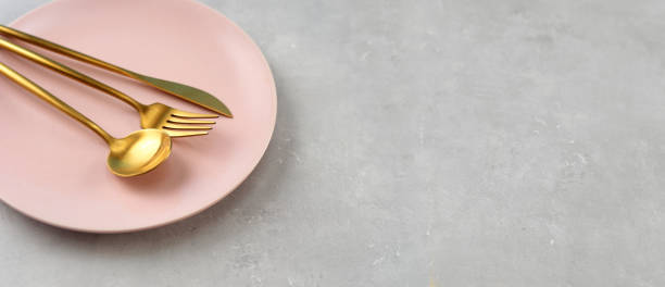 istock Beautiful pink plate and gold cutlery on grey background 1209320556