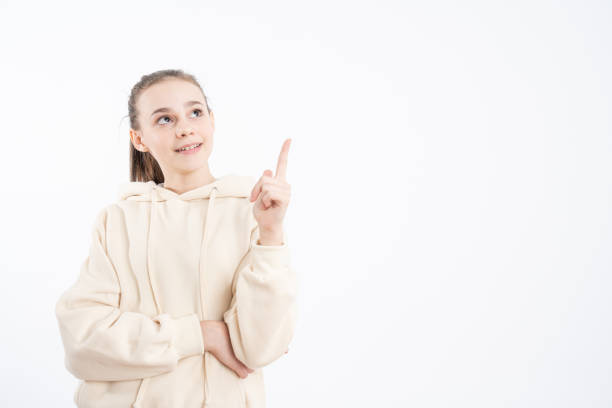 istock Overjoyed young woman points aside with fore finger, isolated over white background, dressed in casual clothing 1209322067
