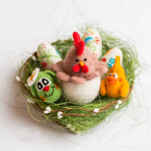 istock decorative colored Ester chicken, bunnys and eggs  in a straw on a white the background. Made of wool 1209324051