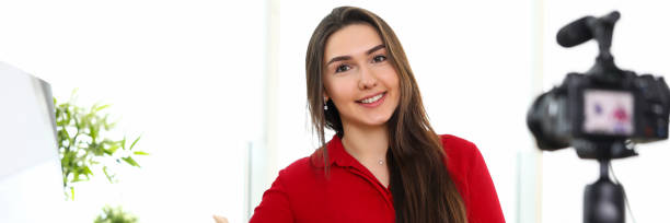 istock Young woman sitting in office opposite camera on tripod 1209334022