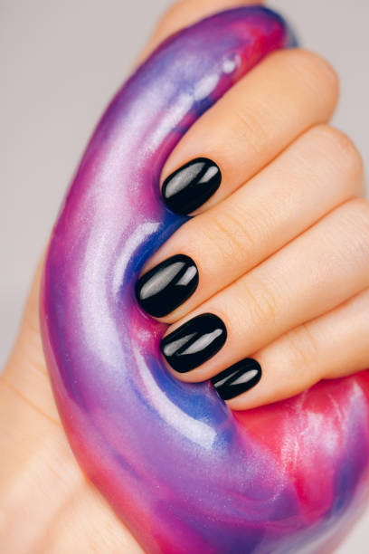 hands with black manicure holding slime