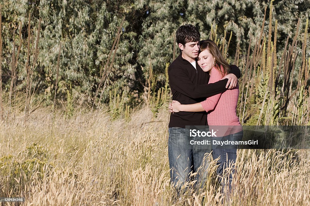 Young Romantic Couple Embracing Outdoors in Nature Young attractive couple embracing in a sunny field. 20-24 Years Stock Photo