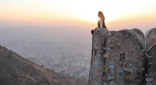 Mature woman looks off from castle wall at sunrise