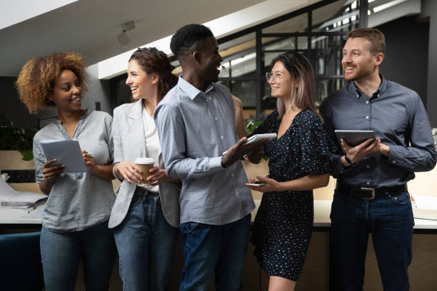 istock Overjoyed multiethnic employees stand laughing cooperating in office 1209353314
