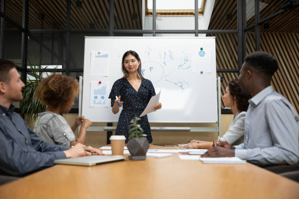 istock Millennial asian woman talk presenting project at meeting 1209353511