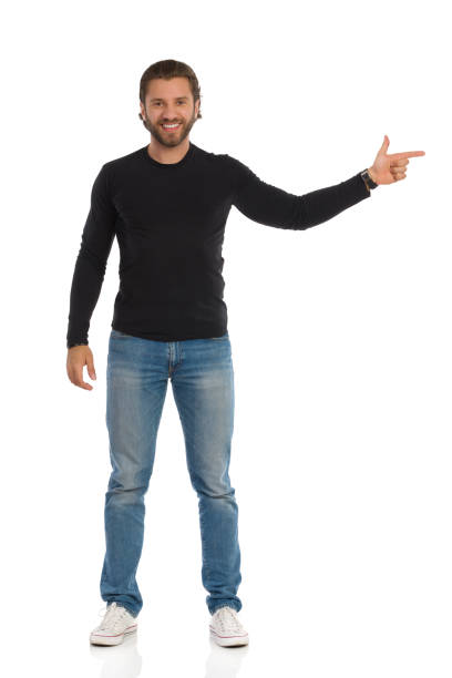 istock Handsome Man In Black Blouse, Jeans And Sneakers Is Pointing At The Side 1209354502
