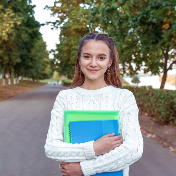 cheerful and joyful teenager girl 12-13-14 years old, summer park holds notebooks, folders textbooks hands. rest school, college study. happy smiling rejoices. knowledge training, education science. - friendship early teens 13 14 years city street imagens e fotografias de stock