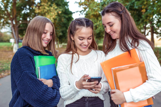 3 girls teenagers 12 13 14 years, summer park, holding smartphone hands, selfie photo. Holiday weekend, friends, emotions of happiness fun smile. Social networks on Internet, online application. 3 chicas adolescentes, smartphone. fin de semana de vacaciones, mejores amigos, emociones felicidad sonrisa divertida, carpetas libros de texto. escuela de descanso, estudio universitario. la sonrisa feliz se alegra. conocimiento, ciencias de la educación