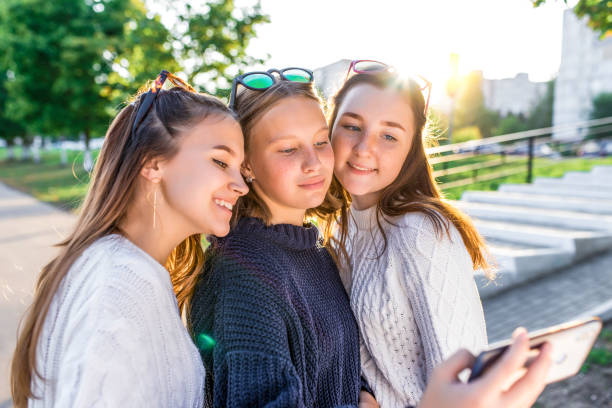 3 dziewczyny nastolatki 12 13 14 lat, letni park, trzymając smartfon za ręce, selfie zdjęcie. weekend wakacyjny, najlepsi przyjaciele, emocje szczęścia zabawa uśmiech. sieci społecznościowe w internecie, aplikacja online. - 13 14 years teenage girls 12 13 years outdoors zdjęcia i obrazy z banku zdjęć