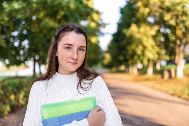 teenager girl 12-13-14 years old, summer park holds notebooks, folders textbooks in hands. rest school, college, serious look, free space copy text. knowledge training, education science. - friendship early teens 13 14 years city street imagens e fotografias de stock