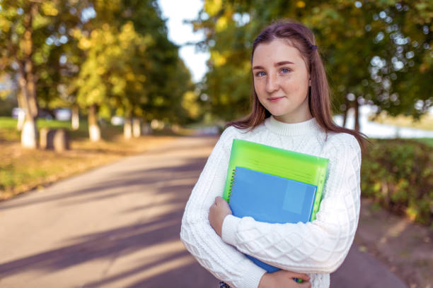 adolescente de 12-13-14 ans, le parc d’été tient des cahiers, des dossiers manuels mains. école de repos, collège étudier les activités de plein air. le sourire heureux se réjouit. formation aux connaissances, sciences de l’éducation. - 12 13 years 13 14 years learning education photos et images de collection