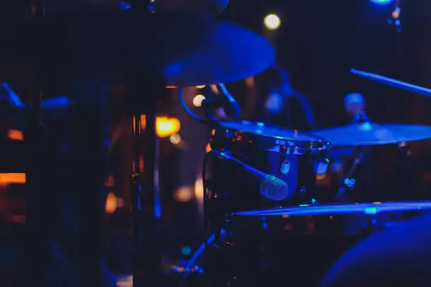 The man is playing drum set in low light background
