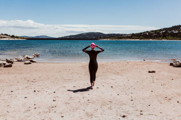 mujer de unos 40 años con un neopreno y esperando para nadar en el lago. concepto de triatlón - swimming exercising women back fotografías e imágenes de stock