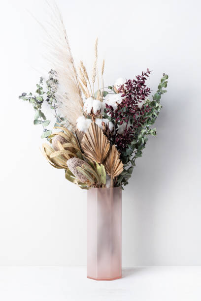 Dried flower arrangement in a pink vase. stylish modern dried flower arrangement in a pink vase. Eucalyptus leaves, banksia, cotton flower ,gold palm, pampas grass and ruscus leaves. Art deco Boho gift for Anniversary, birthday, Mother’s Day, Valentine’s Day or any celebration. pampas photos stock pictures, royalty-free photos & images