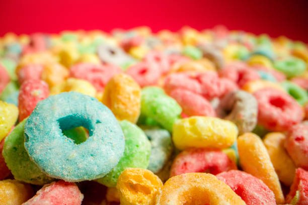 istock Macro Close-Up Wide Angle Shot of Sugary Colorful Fruit Loop American Breakfast Cereal Spread Out on a Red Background 1209364224