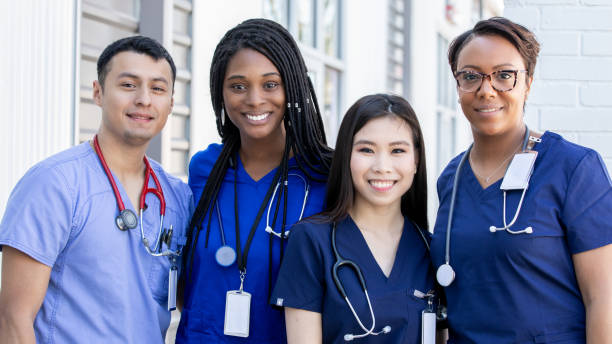 grupo diverso de cuatro estudiantes de enfermería de pie juntos al aire libre - nurse fotografías e imágenes de stock