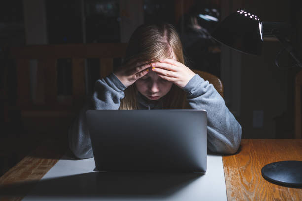 Stressed teen girl working/studying. Stressed teen girl working/studying with a laptop at night on a desk. boring homework twelve stock pictures, royalty-free photos & images