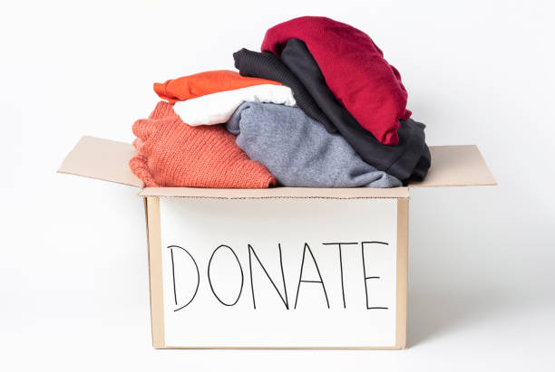 istock Knitted clothes in cardboard box and the inscription Donate on a white background. 1209374484