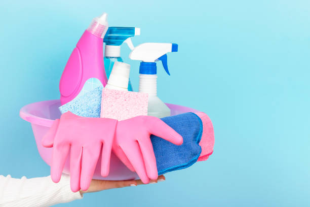 istock Female hand holds basin with detergents and gloves side view, blue background 1209374487