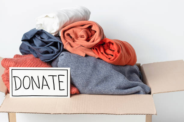 istock Clothes in cardboard box and the inscription Donate on a white background, front view 1209374492
