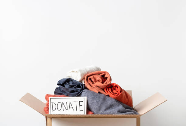 istock Clothes in cardboard box and the inscription Donate on a white background, front view, copy space 1209374495