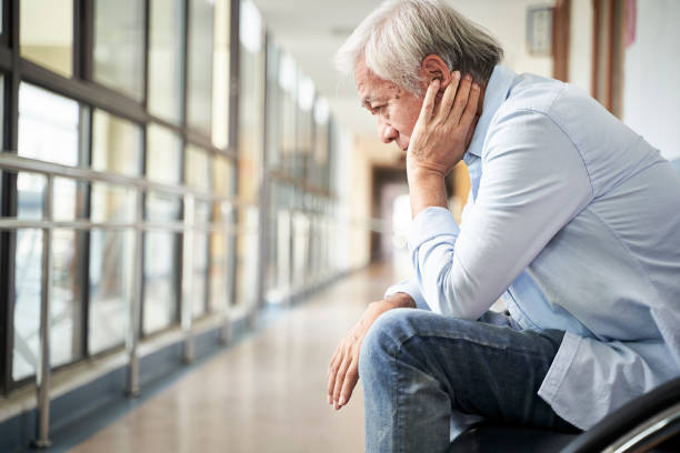 asian old man sitting in hospital hallway looking sad and depressed stock photo